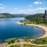 Ceny uhlí v Čechách a uhelná turistika — Muzea, doly a rekultivovaná jezera 3 Rekultivované jezero s písečnou pláží a historickou těžní věží v Čechách